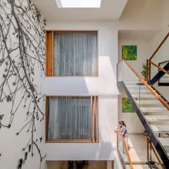 The staircase and the 'Tree of Life' metal artwork are designed to be viewed together. The natural light from the skylight above illuminates both, creating a dramatic and artistic core that is visible from multiple points within the villa.