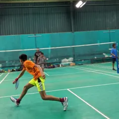 An action shot of a junior player moving quickly across the court during a badminton drill. Our training emphasizes agility and quick reflexes.