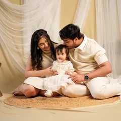 A tender kiss for their little one. This indoor family portrait session, styled with neutral tones and soft fabrics, creates a warm and intimate atmosphere perfect for capturing gentle family moments.