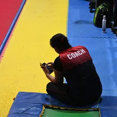 A coach takes a moment to review notes and scores during a competition. Our coaching staff is deeply invested in every athlete's performance.