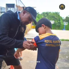 More than just a coach. Here, our head coach helps a young player with his captain's armband before a match. We believe in building leaders on and off the pitch through personal guidance and mentorship.