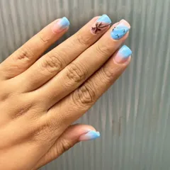 Another angle of the beach-themed nails, showing the palm tree and bird details on a soft blue gradient.