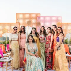 The bride with her bridesmaids at a vibrant outdoor Mehendi. The colorful geometric backdrop and bright floral decor created the perfect setting for fun group photos.