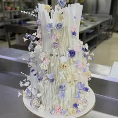 A full view of this custom wedding cake, where I used wafer paper to create delicate, flowing ruffles. The soft pastel sugar flowers add a touch of romance, making it a truly dreamy centerpiece for a special day.