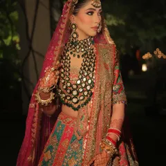 A stunning three-quarter shot of this magnificent bridal look. The makeup is strong and defined, designed to hold its own against the heavy embroidery and statement polki and emerald jewelry.