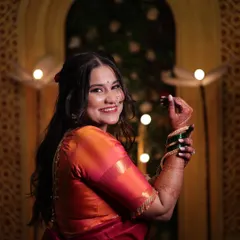 A playful and happy moment from her Mangla Gaur puja. The makeup is traditional yet fresh, perfectly complementing her orange and red silk saree.