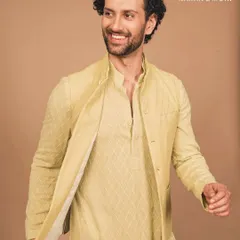 Sunlit elegance for the modern gentleman. This pastel yellow kurta and Nehru jacket set blends festive charm with understated sophistication. The quilted texture on the jacket adds a layer of subtle detail, perfect for a Haldi ceremony or a spring wedding.