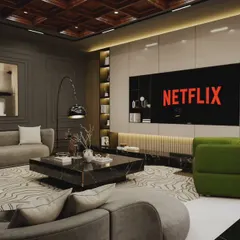 A modern entertainment room designed for relaxing and watching movies. The space features a large screen, comfortable curved sofas, and pops of green from the armchairs, all set against a sophisticated grey and wood palette.