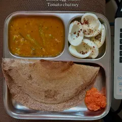 A healthy South Indian breakfast of ragi dosa served with sambar, boiled egg whites, and tomato chutney.