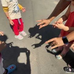 An educator helps children make animal shapes with their hands, watching the shadow puppets come to life on the ground. This playful activity makes learning about light and shadow interactive and fun.