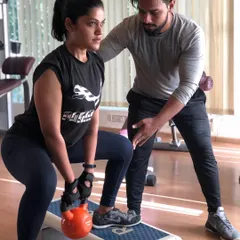 Proper form is everything. Here, I am guiding a client through a kettlebell squat, ensuring her technique is perfect to maximize results and prevent injury. This is the level of personal attention you get in every 1-on-1 session.