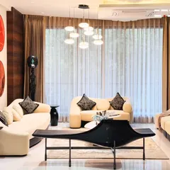 Natural light floods this living room, highlighting the clean lines of the furniture and the contrast between the dark wood paneling and the light-colored sofas.