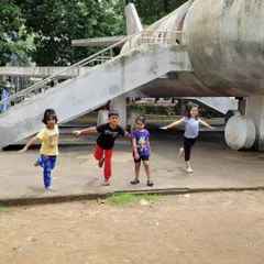 The kids are having fun with Virabhadrasana III (Warrior III Pose), pretending to be airplanes. Incorporating imagination and play helps children engage deeply with the practice and its benefits.