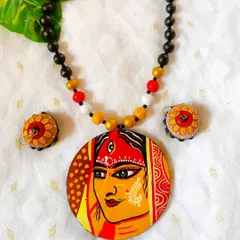 I pour my heart and devotion into these hand-painted pendants. This piece features the serene face of a goddess, detailed with traditional motifs, making it perfect for festive occasions or as a piece of wearable art. The necklace is strung with terracotta beads that complement the pendant.