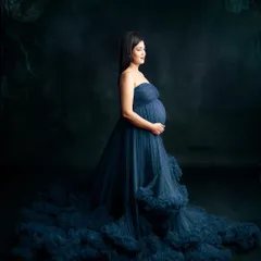 A stunning portrait featuring a deep blue gown with a cloud-like tulle train. The dark, moody background makes the color pop, creating a sense of drama and enchantment.