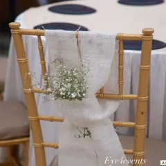 We carry the decor theme through to every element, including the seating. Here, a simple golden chair is elevated with a rustic burlap sash and a small posy of baby's breath, adding a touch of charm.