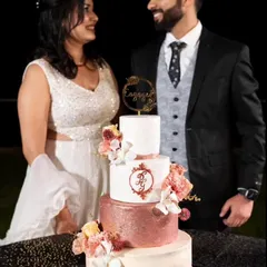 A truly special moment seeing a couple with the four-tiered engagement cake I crafted for them. This design features a rose gold glitter tier, a custom monogram, and an ombre fade, all adorned with delicate flowers.