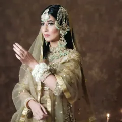 A model in a golden lehenga and mint-green jewellery, showcasing a soft and elegant look.
