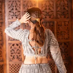 This stunning grey lehenga is all about intricate details. The full-sleeve blouse features heavy silver embroidery and a beautiful tie-up back design, perfect for a sangeet or reception look.