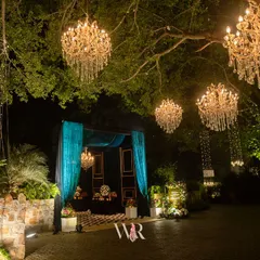 We love turning natural elements into features. Here, chandeliers hang like jewels from a majestic tree, creating a captivating entrance and setting a mood of whimsical elegance for this engagement night at Morbagh, Delhi.