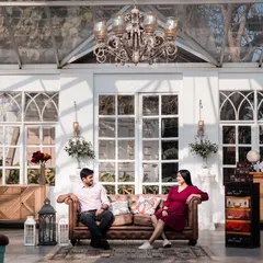 A beautifully composed shot in a glasshouse cafe. The elegant chandelier and rustic furniture create a chic, sophisticated setting for a modern couple's portrait.