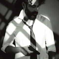 A thoughtful profile shot in black and white. The dramatic lighting carves out his features, creating a strong and sculptural portrait.