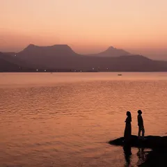 A stunning silhouette of a couple against the fiery sunset over Pawna Lake. We use the dramatic colors of the sky to create breathtaking and romantic backdrops for our pre-wedding photoshoots.