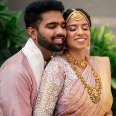 A tender moment between the couple. The bride's makeup in soft pink tones perfectly matches her beautiful silk saree, creating a harmonious and romantic look.