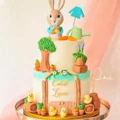 I brought the world of Peter Rabbit to life with this two-tiered buttercream cake. It features a hand-sculpted Peter Rabbit figure, a garden scene with tiny carrots and ducklings, and a personalized nameplate, making it a magical centerpiece for a first birthday.