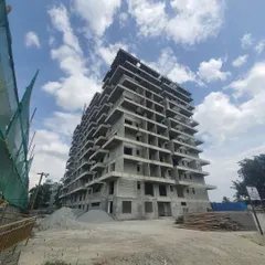 A wider view of the apartment building under construction. You can see the raw concrete frame rising against the sky, giving a sense of the project's scale.