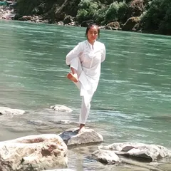 A balancing pose with closed eyes on an uneven surface by the river. This is a true test of mental calm and focus, the essence of yoga.