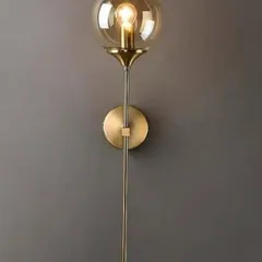 This industrial-inspired globe sconce features a tinted glass ball on a slender gold-finished metal rod. The transparent shade allows the bulb to be a design element, adding a vintage touch to a modern fixture.