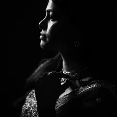 Another perspective from our low-key portrait series, this black and white image captures a contemplative and elegant mood. The interplay of shadow and light creates a powerful, sculptural effect.