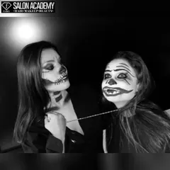 A black and white photo of two students with skull and clown Halloween makeup, highlighting the strong contrast and line work achieved through our training.