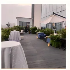 The setup for a rooftop event during the day, showing the arrangement of cocktail tables and lounge seating before guests arrive.