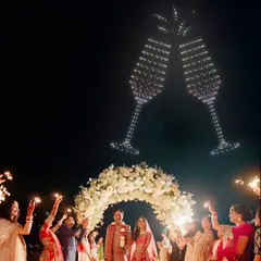 Let's toast to your new beginning in the grandest way possible. Here, I've created giant, clinking champagne glasses in the sky, perfectly timed to celebrate the couple's union as their guests cheer them on with sparklers.