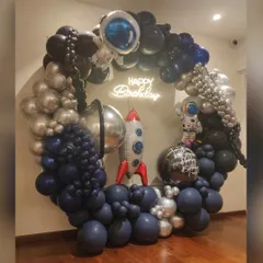 To infinity and beyond! We created this spectacular spaceship-themed organic balloon ring for a young astronaut's birthday. The design features a full circle of balloons in deep space blues, blacks, and metallic silvers, complete with astronaut and rocket ship foils, and a glowing "Happy Birthday" neon sign at the center.