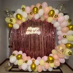 A lovely pastel balloon ring against a rose gold fringe curtain. This setup in soft pink, yellow, and white, with gold star accents, is perfect for a sweet and stylish birthday party.