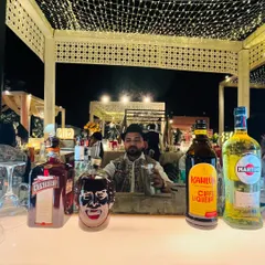 One of our bartenders behind a well-stocked bar, featuring brands like Cointreau, Kahlua, and Martini. This setup is ready for a night of crafting exquisite cocktails.