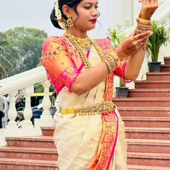 This bride looks effortlessly graceful for her ceremony. She chose a classic off-white silk saree with a pink and gold border, which we paired with a custom hand-embroidered blouse that enhances the traditional elegance of her look.