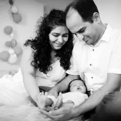 A candid moment on the bed, with parents playing with their newborn's feet. This is what lifestyle photography is all about.