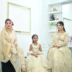 A beautiful family portrait featuring coordinated ivory and gold outfits. The collection includes a sharara set, an anarkali, and a matching kids' lehenga.