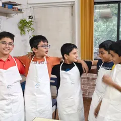 The best part of a pottery party is the fun you have with your friends. These boys are sharing a laugh after their creative session, proudly wearing their aprons.