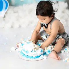 The aftermath of a successful cake smash. This photo captures the pure, sticky joy of a baby enjoying their first taste of birthday cake.