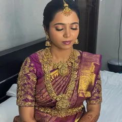 A moment of calm before the ceremony. This shot showcases the full effect of the bridal jewellery, from the nethichutti on her forehead to the layered necklaces and matching jhumkas.