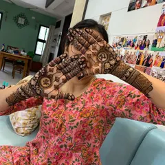 A happy client showing off her personalized mehndi. The initials are clearly visible on her palms, making for a great photo opportunity and a special memory.