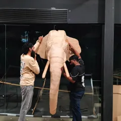 Two of our artists making final adjustments to the cardboard elephant sculpture at our studio. This shot gives a great sense of the piece's scale and the collaborative effort that goes into our work.