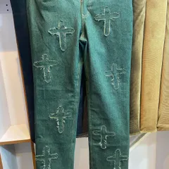 A front view of the custom cross-patch jeans, showing the placement and detail of the appliqué work on the durable green denim.