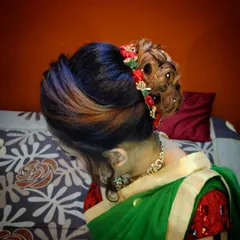 A modern and stylish bridal bun with highlights. I created intricate rose-like curls within the bun and added small red flowers for a pop of color.