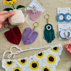 A closer look at some of the custom accessories from a large order. You can see the crochet sunflower pot, leaf-shaped macrame keychains, an evil eye charm, and a sunflower bandana. These small items make for wonderful, personal gifts.